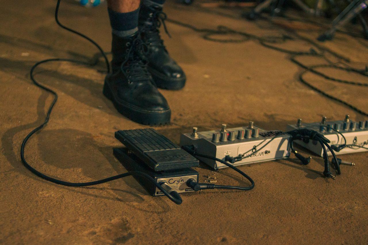 Home Close-up of a musician's feet on a stage with various guitar effects pedals.