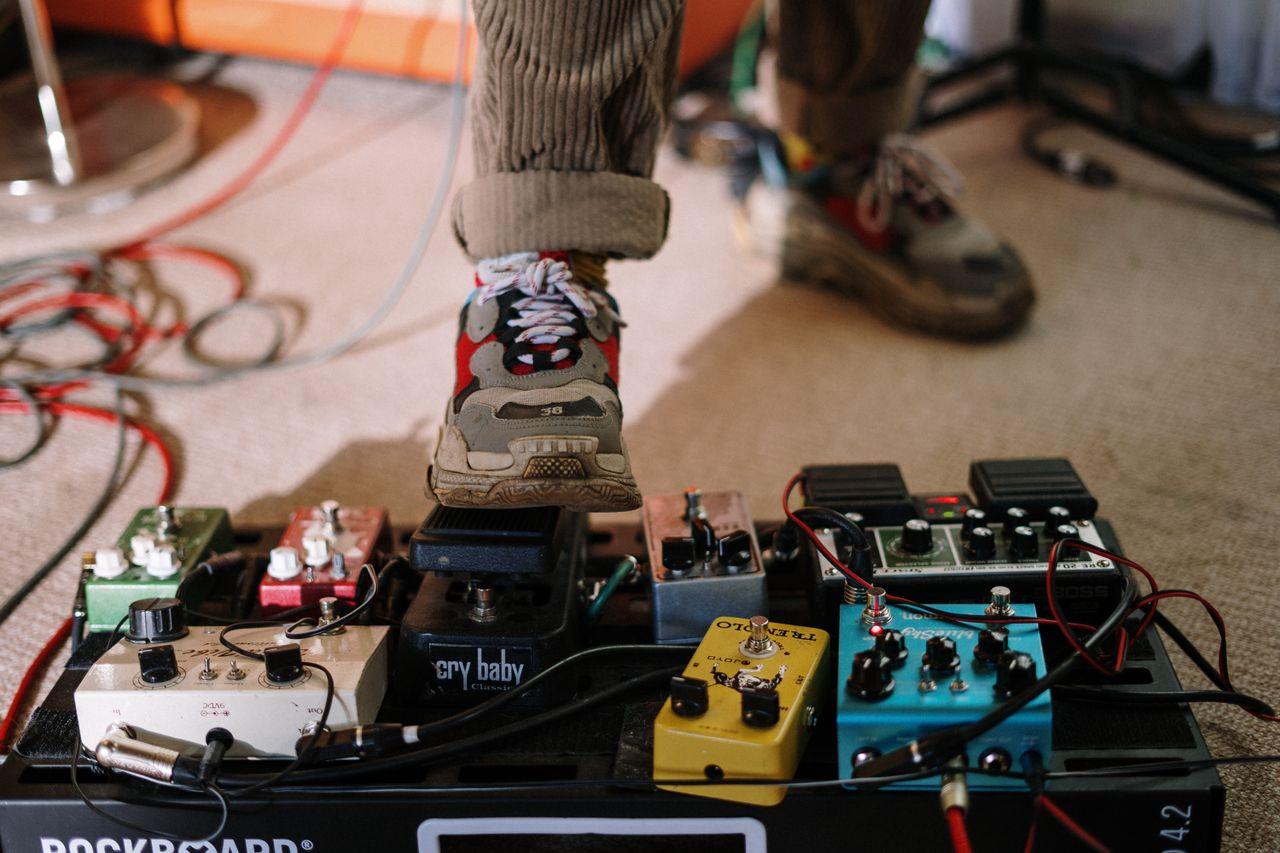 Home Close-up of a musician's foot on a guitar pedal board in a home music studio.